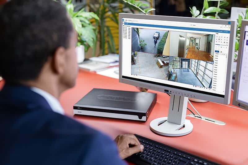 Mitarbeiter betrachtet mehrere Kamerabilder auf einem Monitor neben einem Videorekorder.