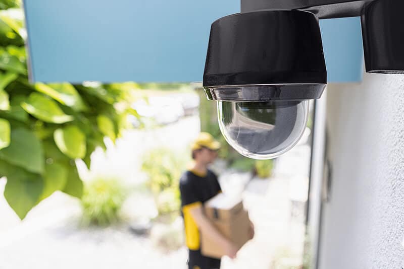 Schwarze Dome-Kamera über einem Gebäudeeingang.