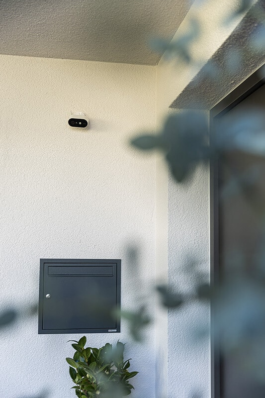 Kleine Überwachungskamera an einer Hauswand über einem Briefkasten.