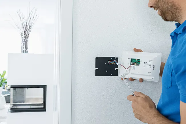 Techniker montiert ein Bedienteil einer Sicherheitsanlage an der Wand.