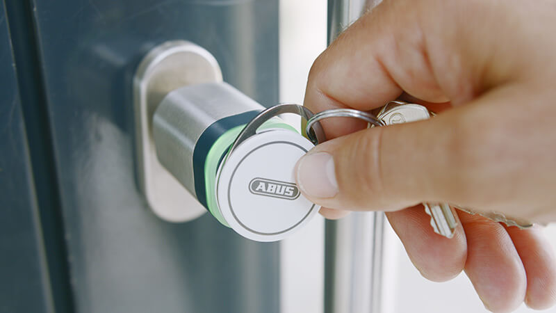 Person bedient einen elektronischen ABUS-Zylinder mit einem Transponder.